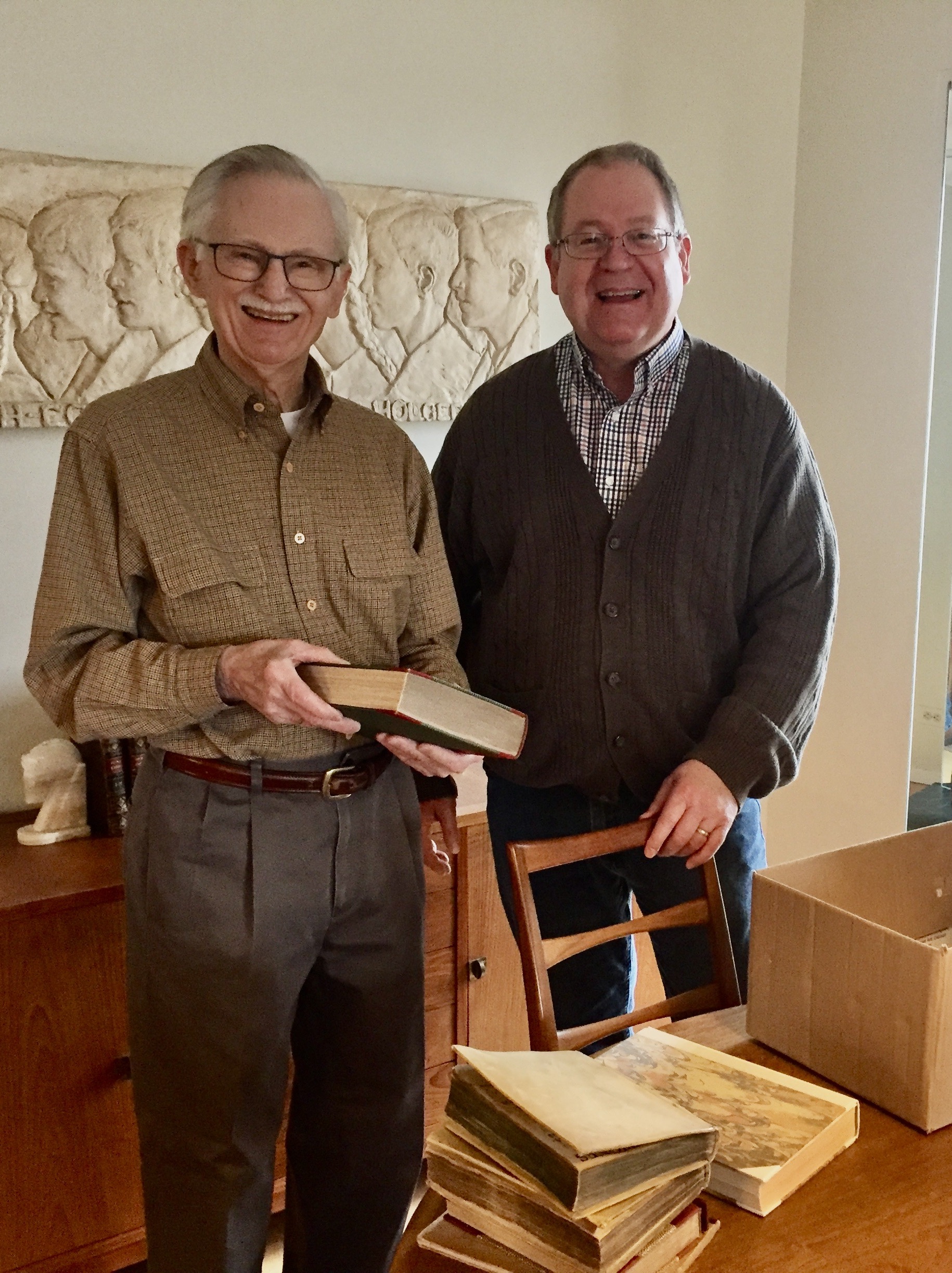 John Christianson (left), at his home in Minneapolis on March 30, 2022, showing Curator Kerry Magruder (right) some of the books being donated.