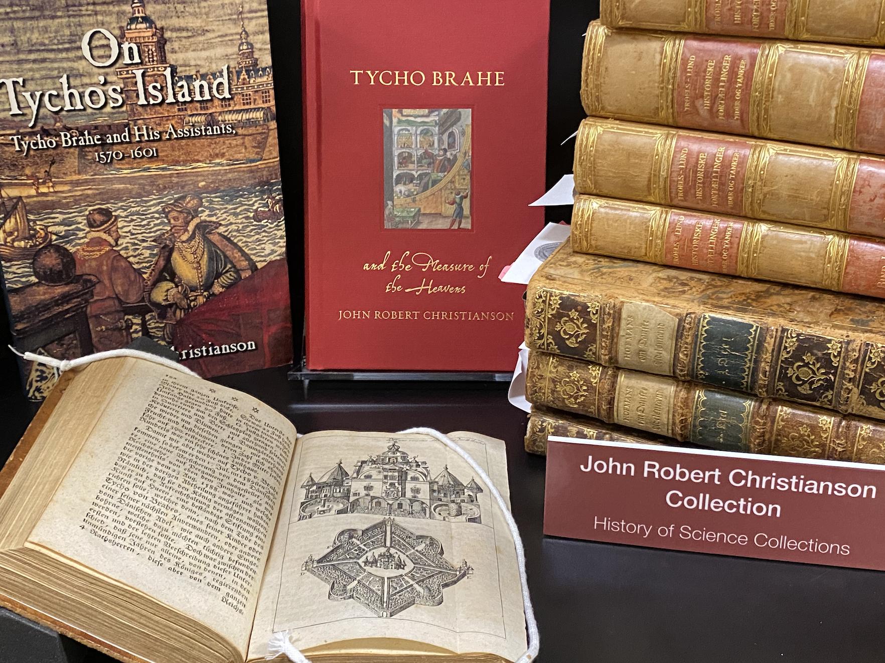 Photo of books on shelf, some with cover, some opened, some stacked (recent works, as we'll as rare books) on the topic of Tycho Brahe
