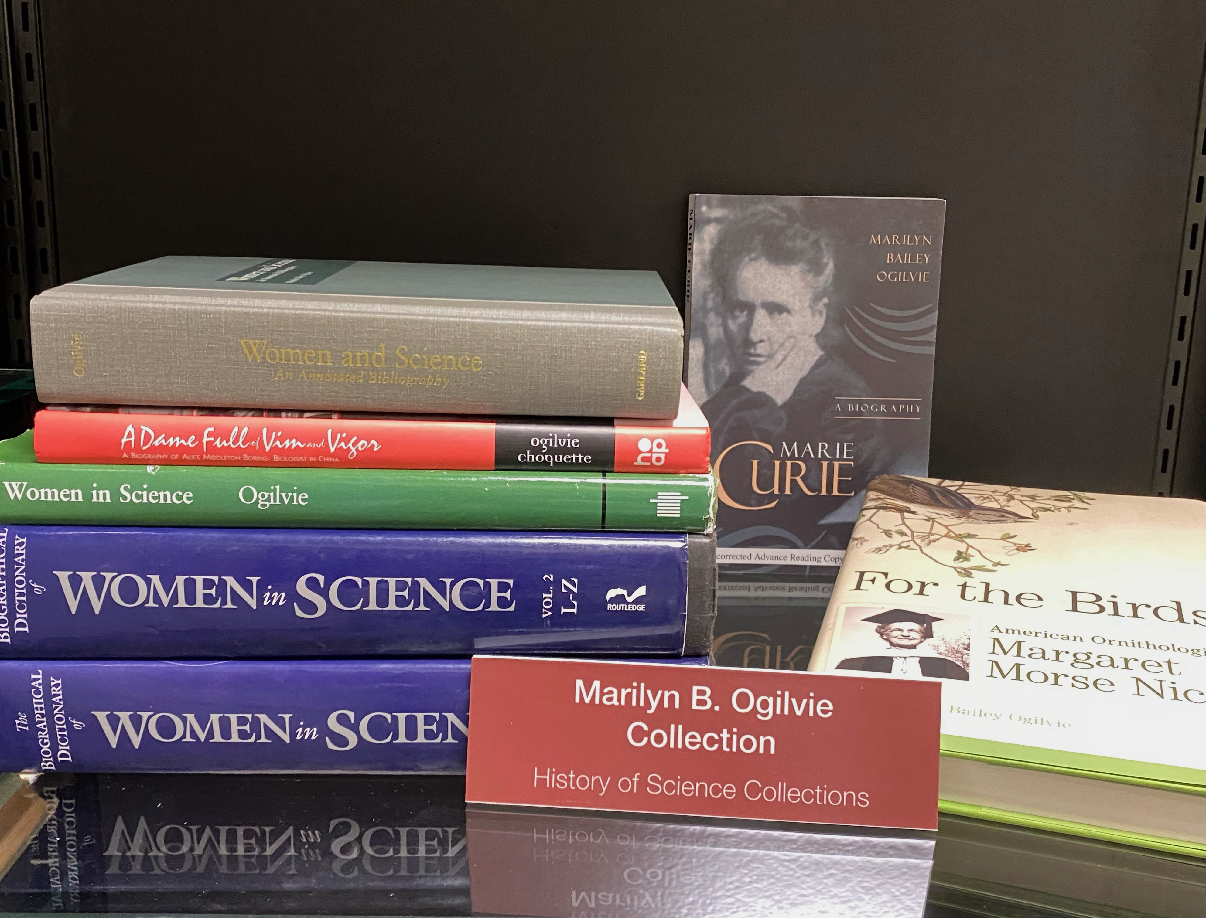 Photo of shelf of books on women and science, with sign "Marilyn B. Ogilvie Collection."