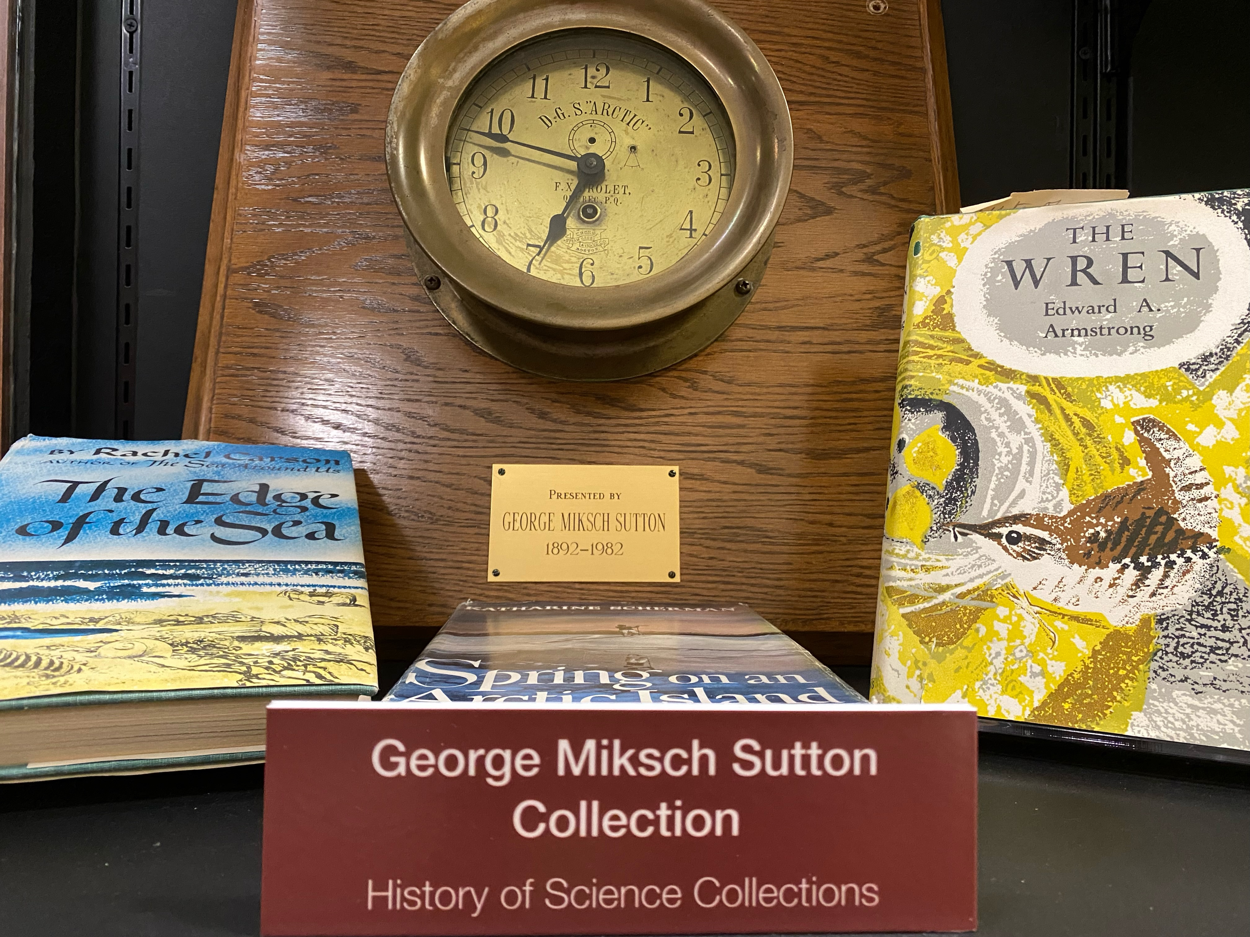 Photo of shelf with materials from the "George Miksch Sutton Collection." Includes two 3 books and clock on plaque