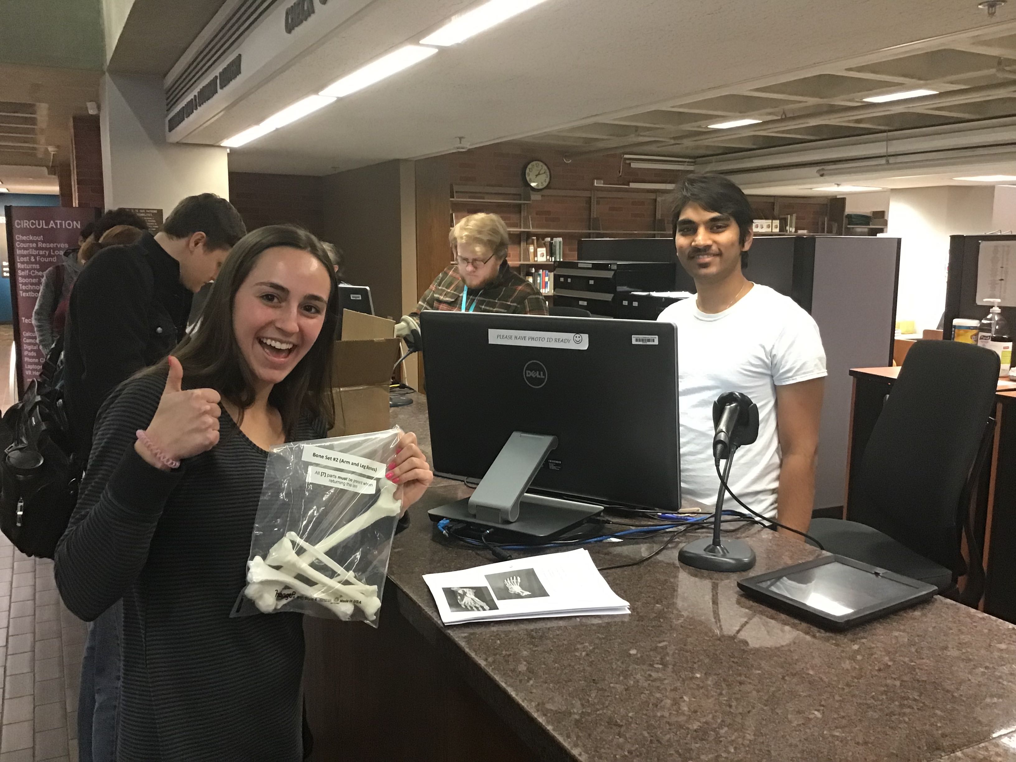 A student checking out 3D printed bones from the circulation desk.